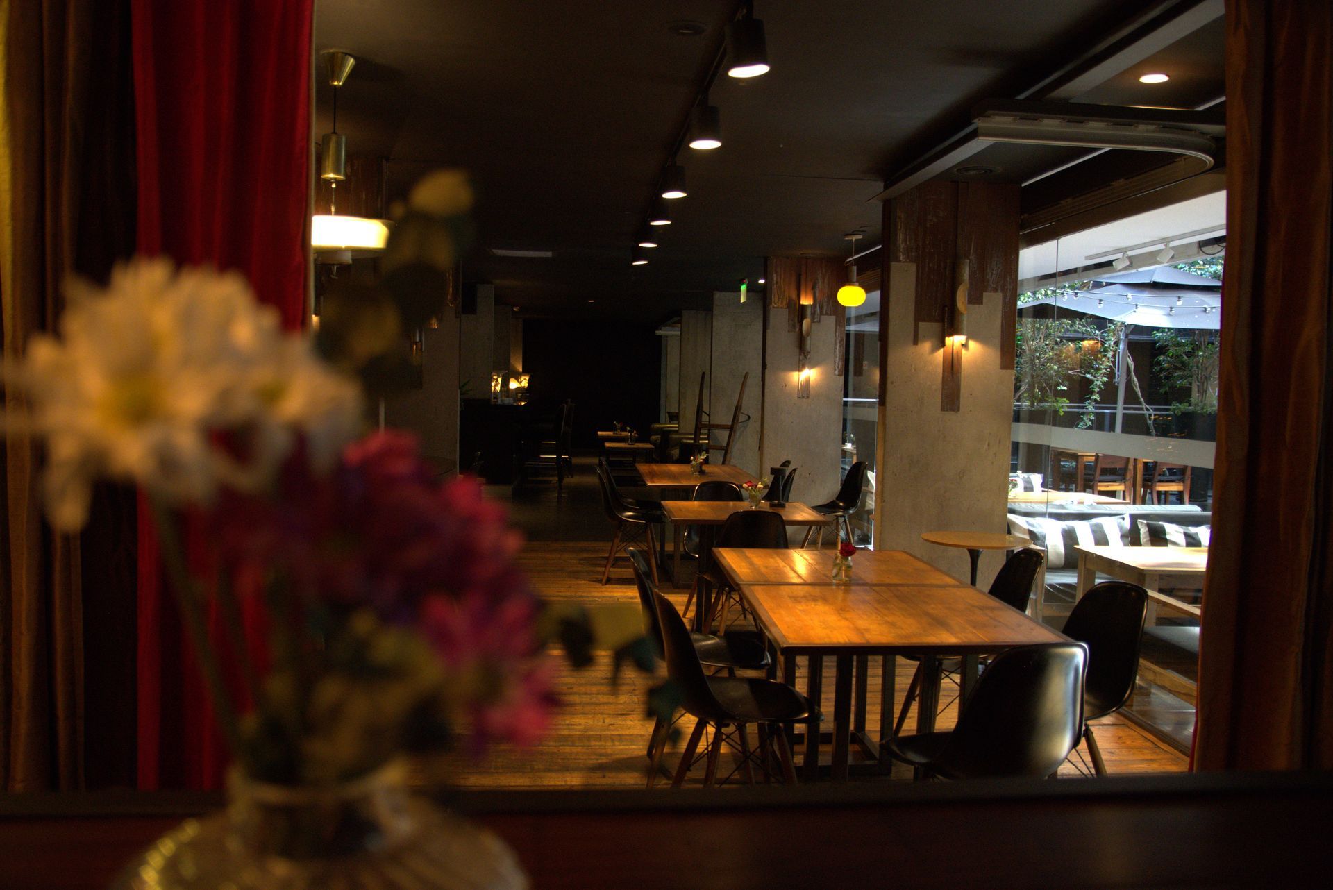 Un restaurante con mesas y sillas y un jarrón de flores en primer plano.