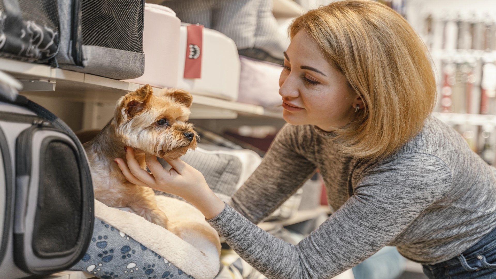 Una mujer acaricia a un perro pequeño en una tienda de mascotas.