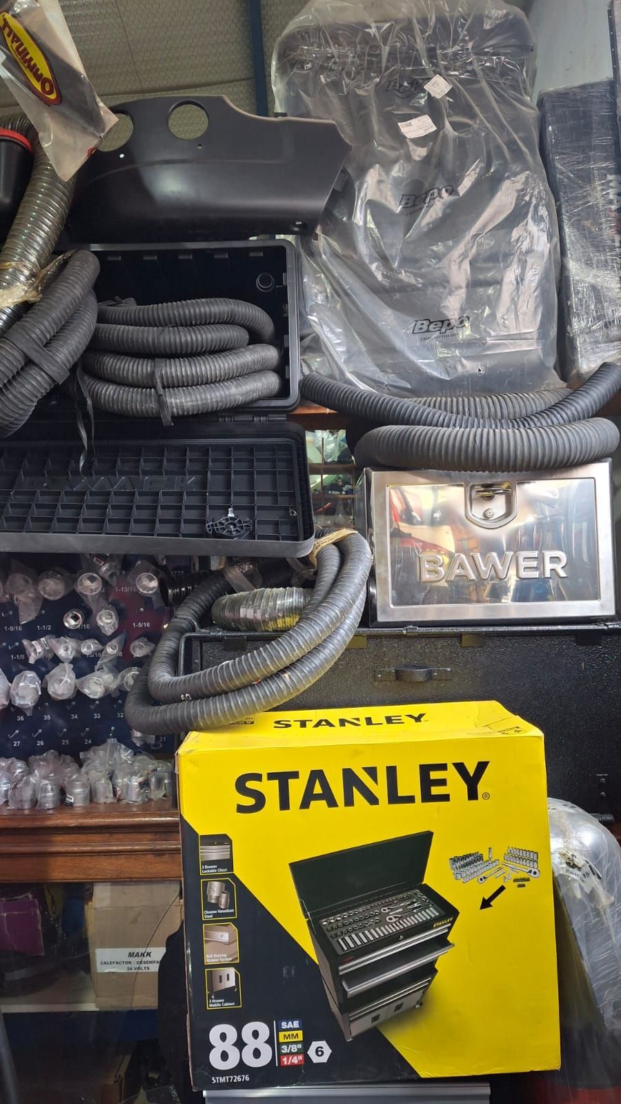 Una caja de herramientas Stanley en una caja amarilla con otras herramientas y piezas exhibidas en un entorno desordenado.