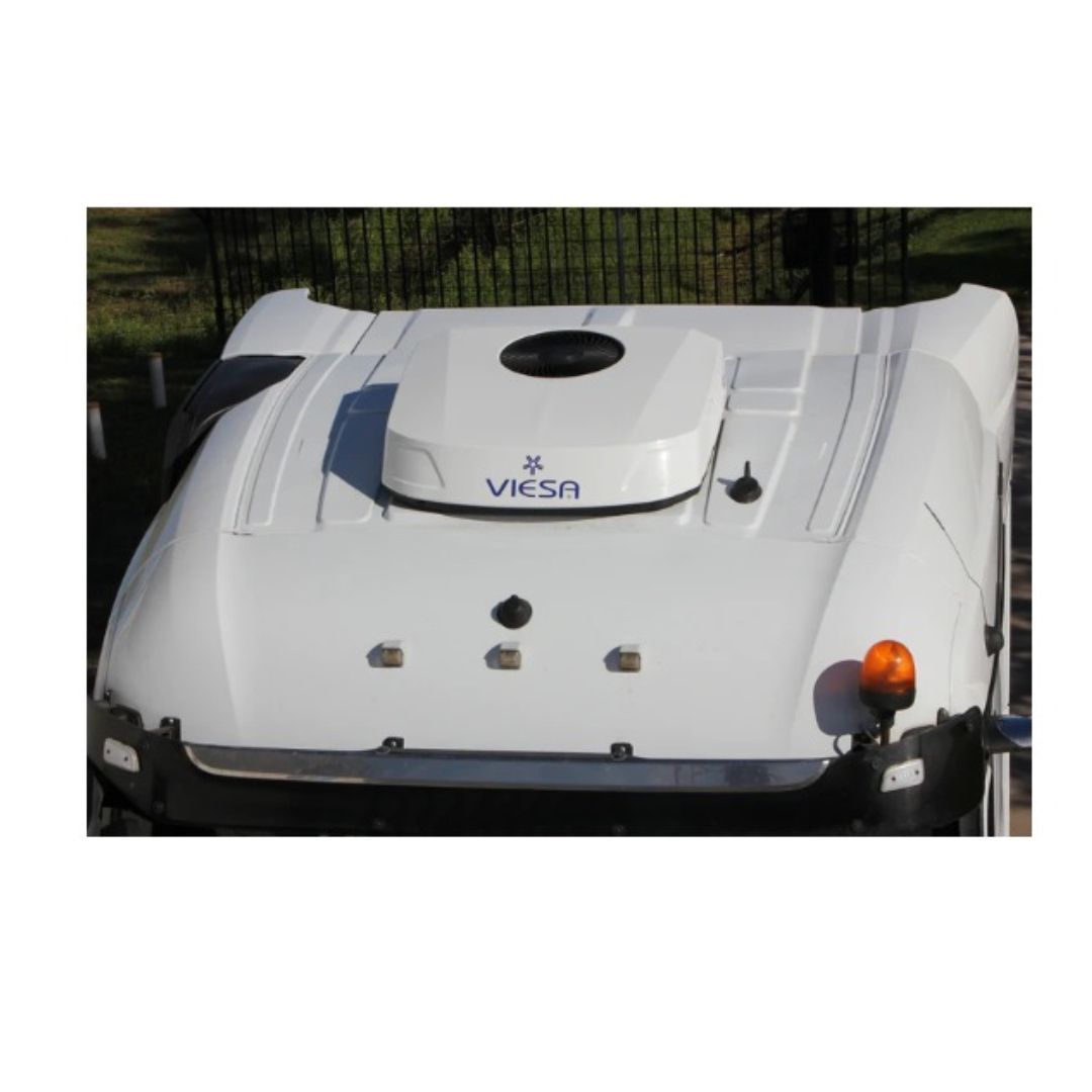 Camiones semirremolques blancos circulando por una carretera a través de un bosque durante la puesta de sol.