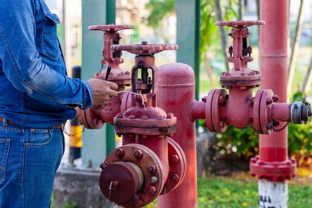 A Man is Working on a Red Pipe With a Wrench — J & N Plumbing Pty Ltd In Kootingal, NSW