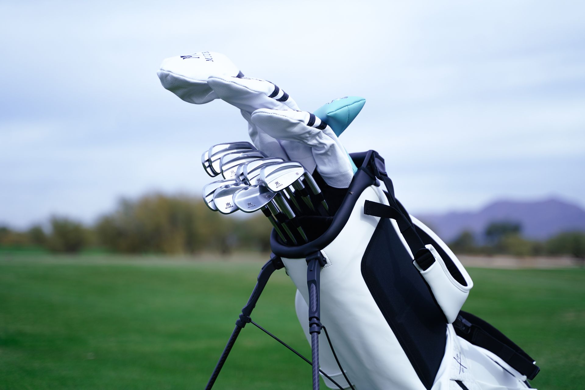 A person is pushing a golf bag full of golf clubs on a golf course.