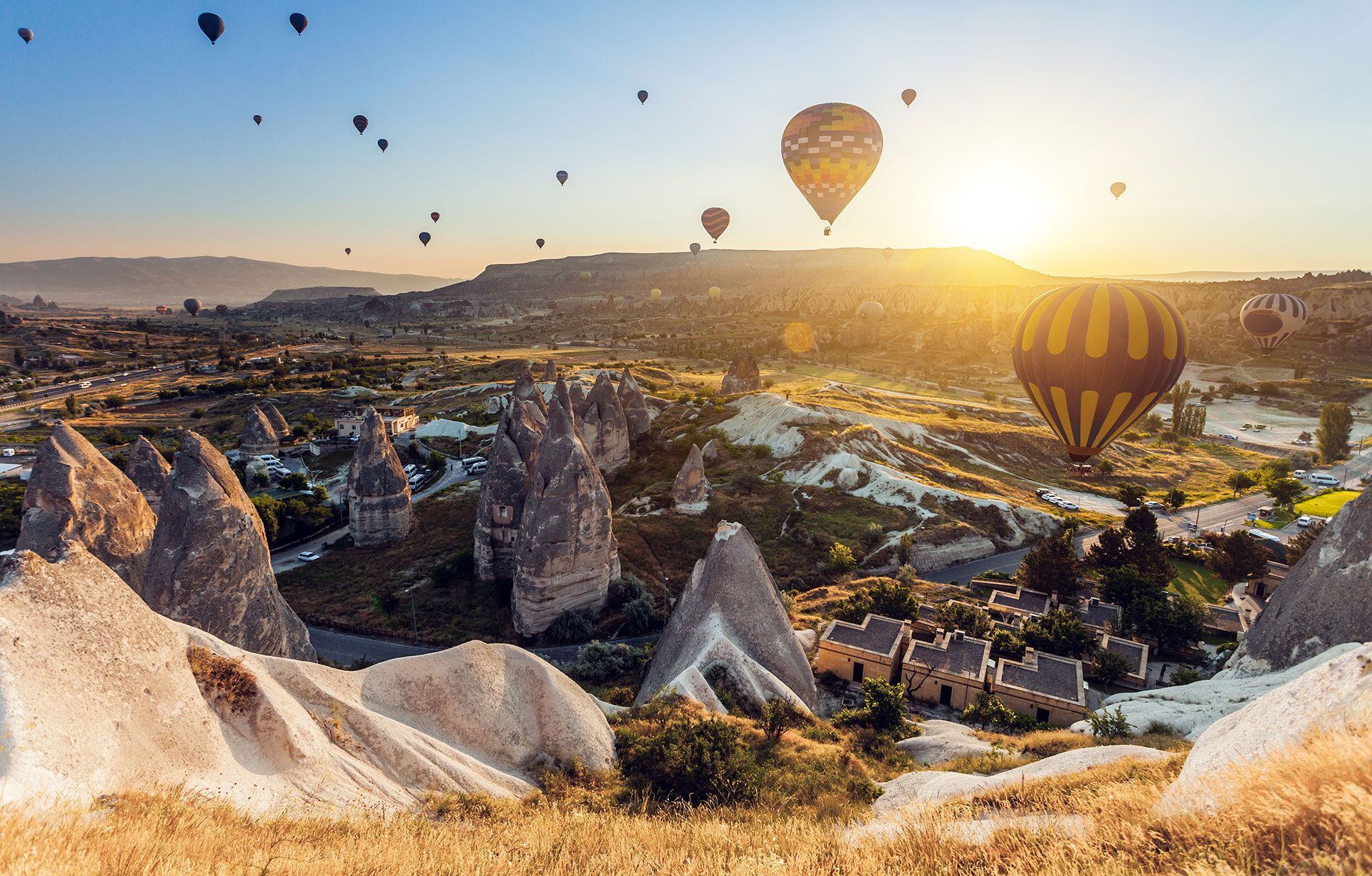 Un grupo de globos aerostáticos volando sobre un paisaje rocoso al atardecer.