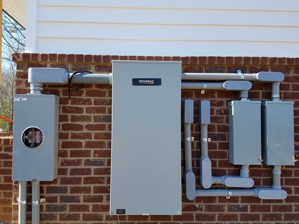 Electrical boxes and conduits mounted on a red brick wall.