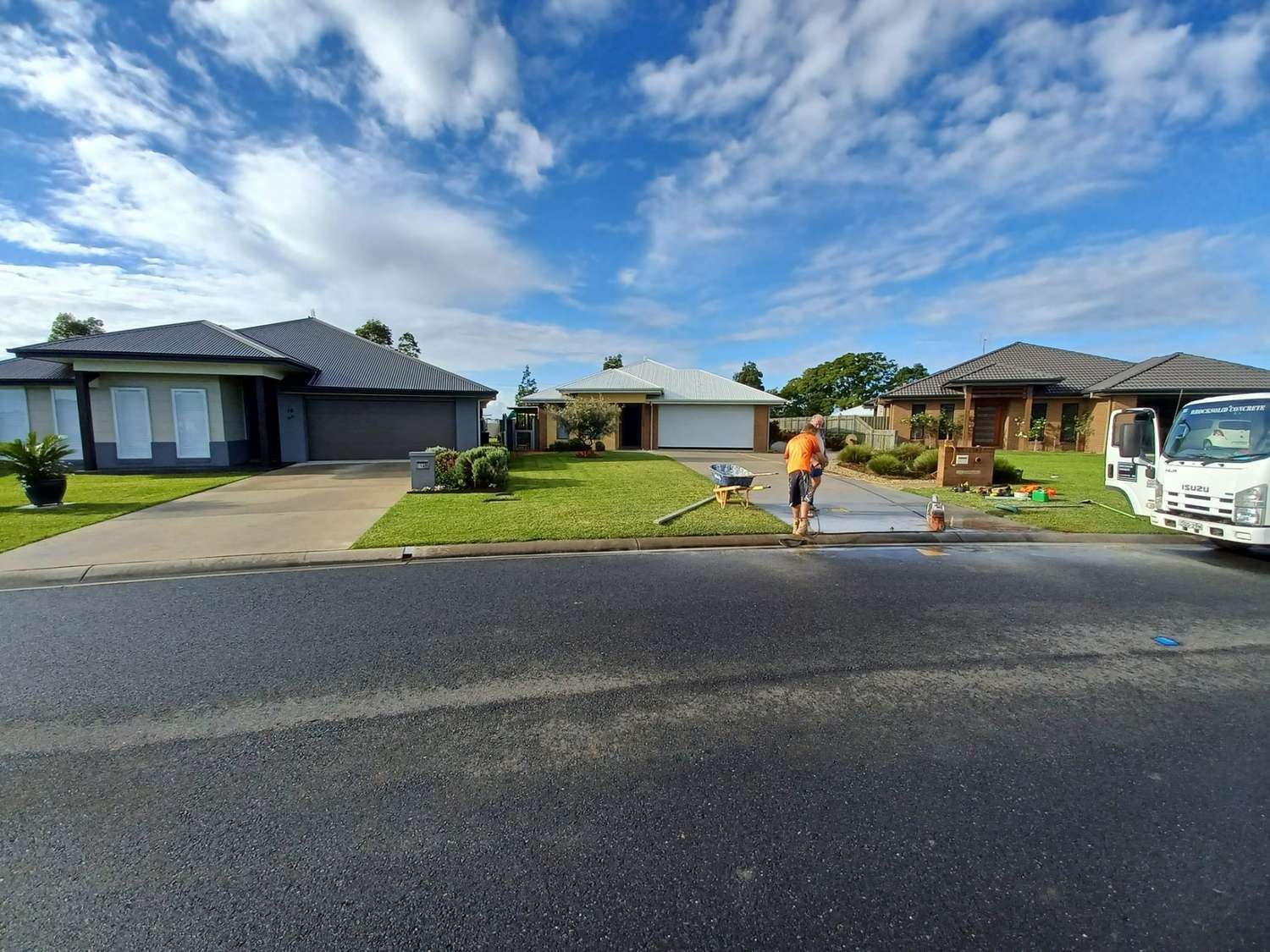 A Man is Cleaning a Driveway in Front of a Row of Houses — Brocksolid Concrete in Pillar Valley, NSW