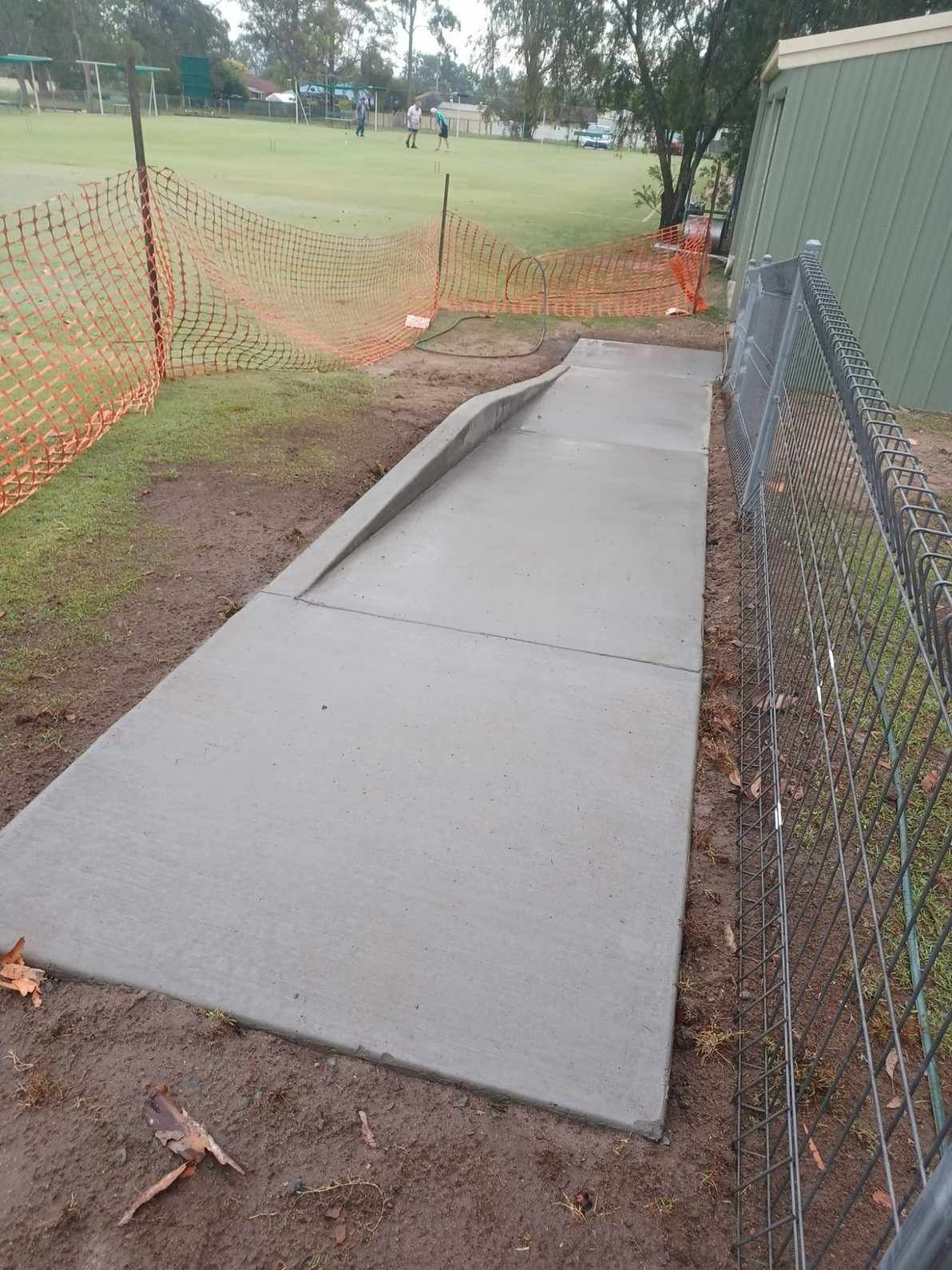 A Concrete Ramp is Being Built in a Park Next to a Chain Link Fence — Brocksolid Concrete in Pillar Valley, NSW