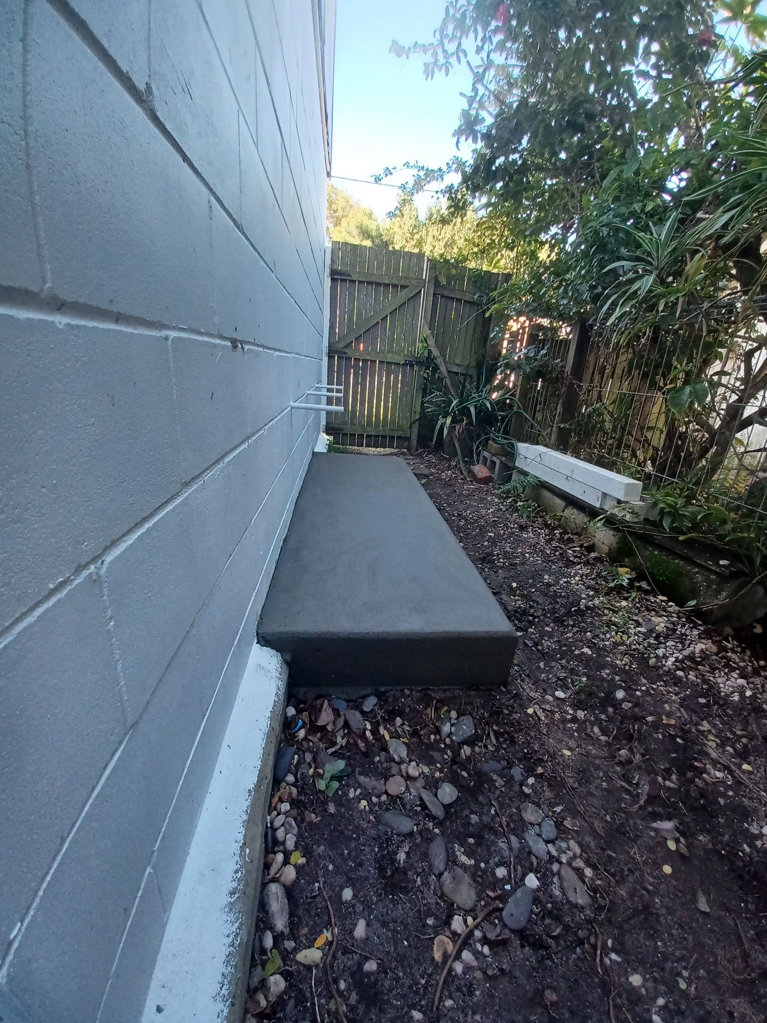 Small concrete slab beside house wall near garden area.— Brocksolid Concrete in Pillar Valley, NSW