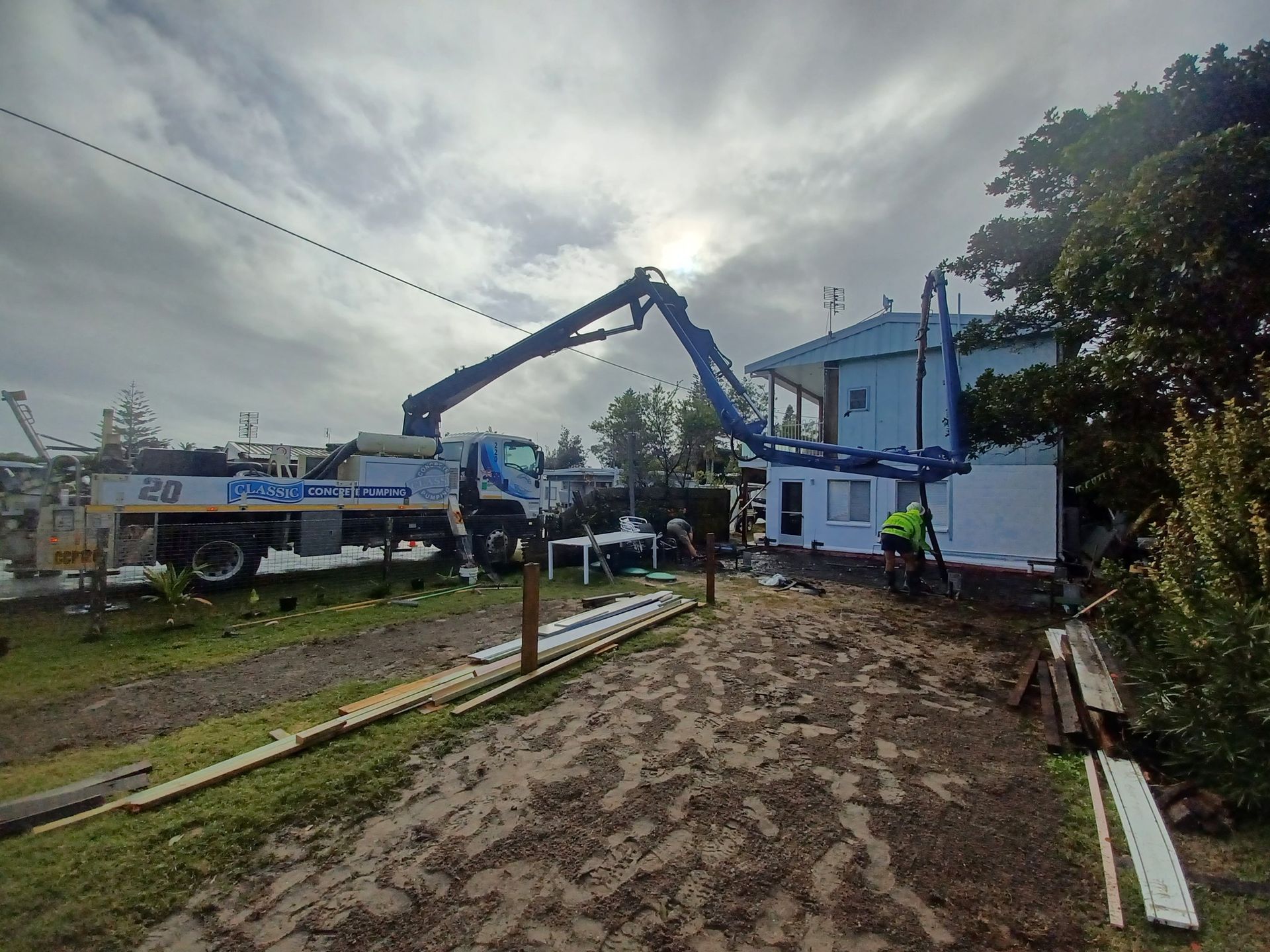 A Small Excavator is Sitting in Front of a House — Brocksolid Concrete in Pillar Valley, NSW