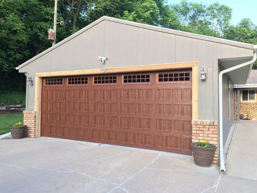A large brown garage door is sitting in front of a house.