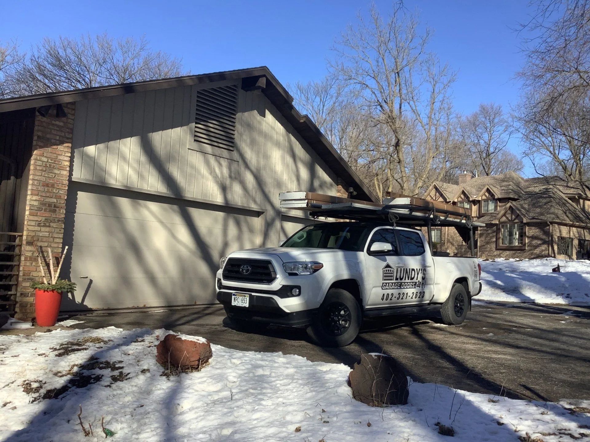 A white truck is parked in front of a house in the snow.