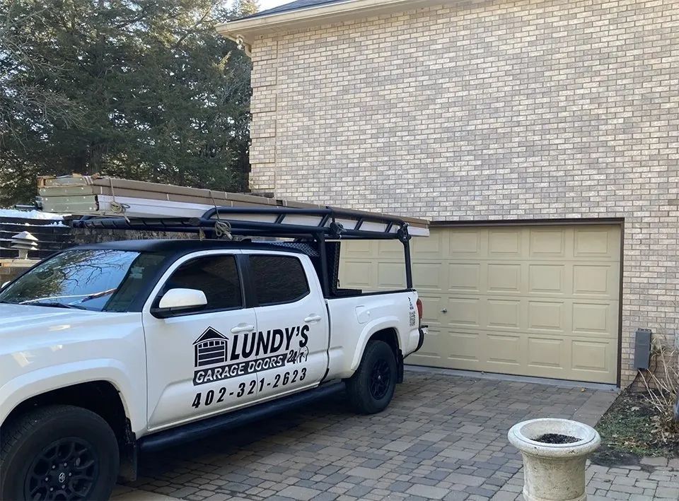 A white truck is parked in front of a garage door.