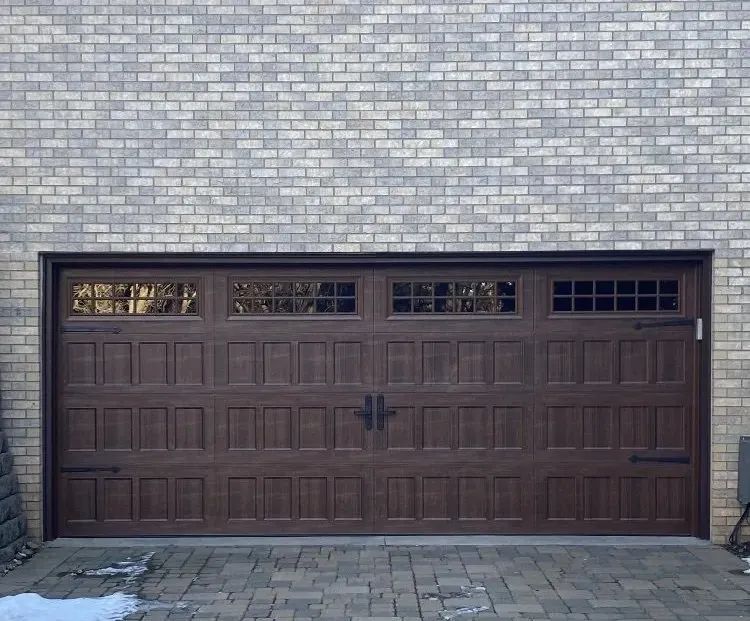 A large brown garage door is on a brick building.
