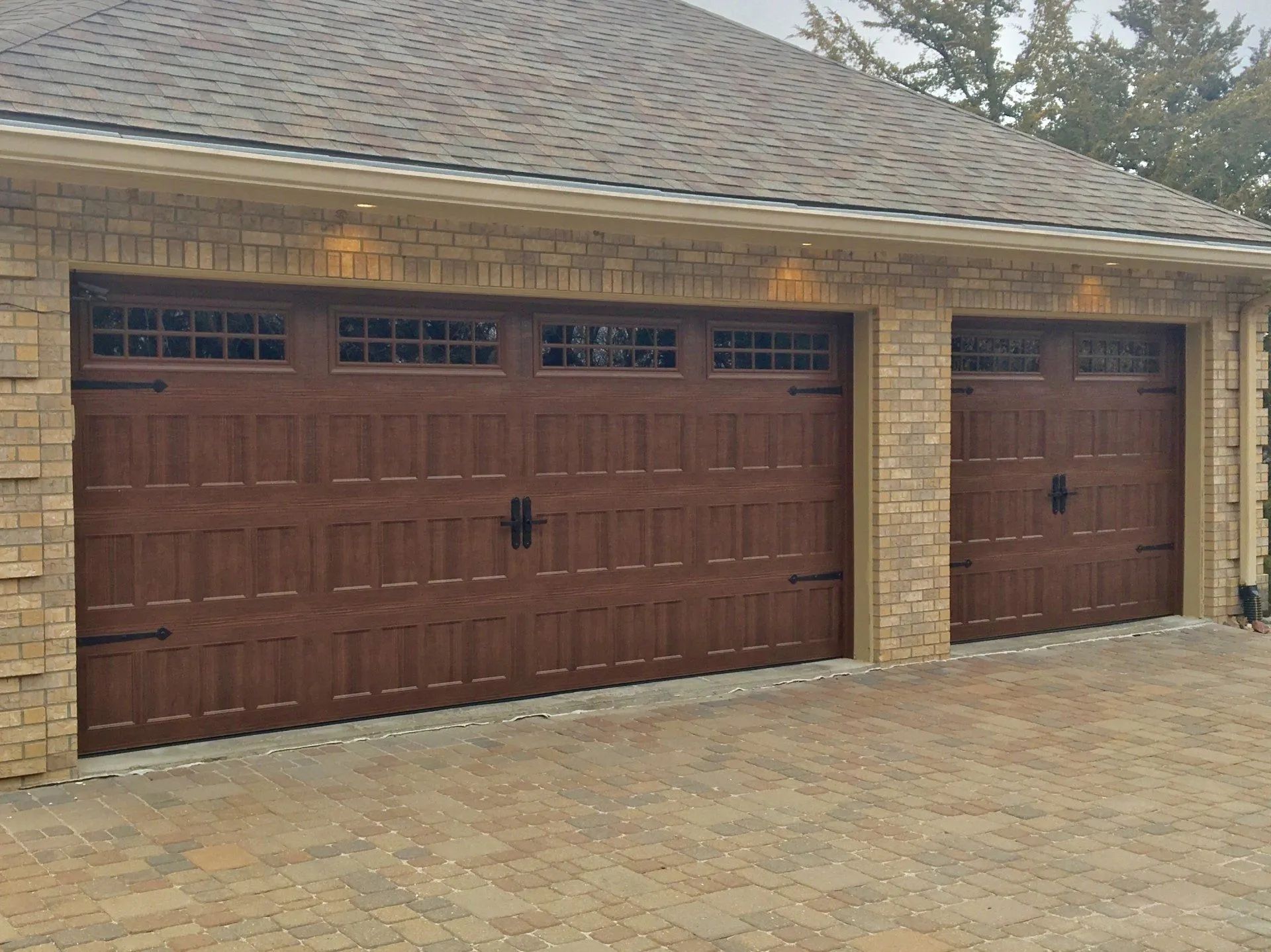 A brick garage with three brown garage doors