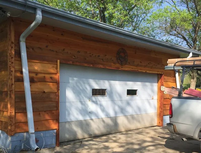 A white truck is parked in front of a wooden garage door.