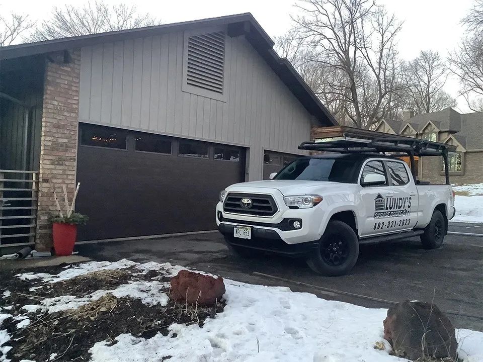 A white truck is parked in front of a garage door.