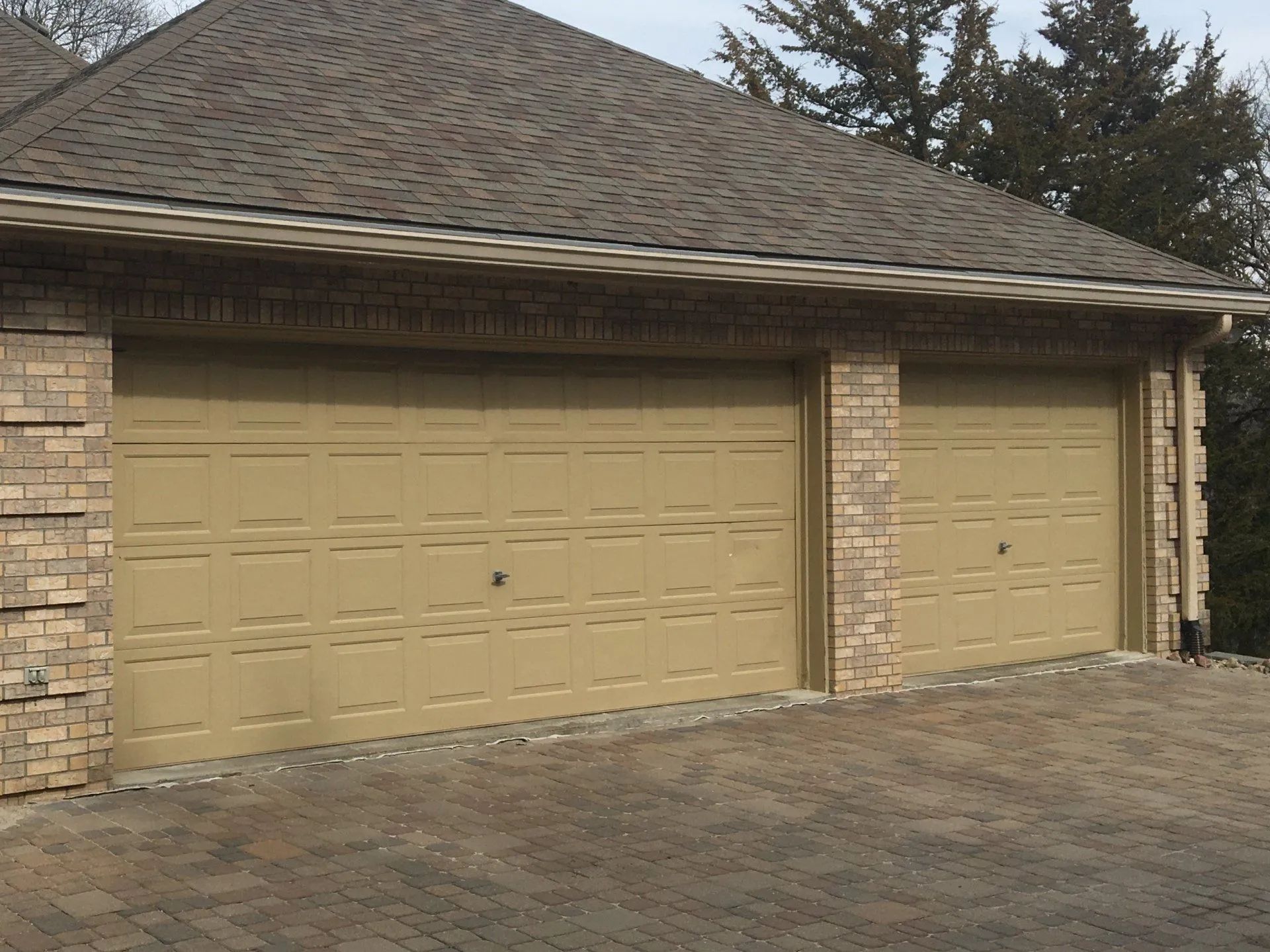 A house with three garage doors and a brick wall