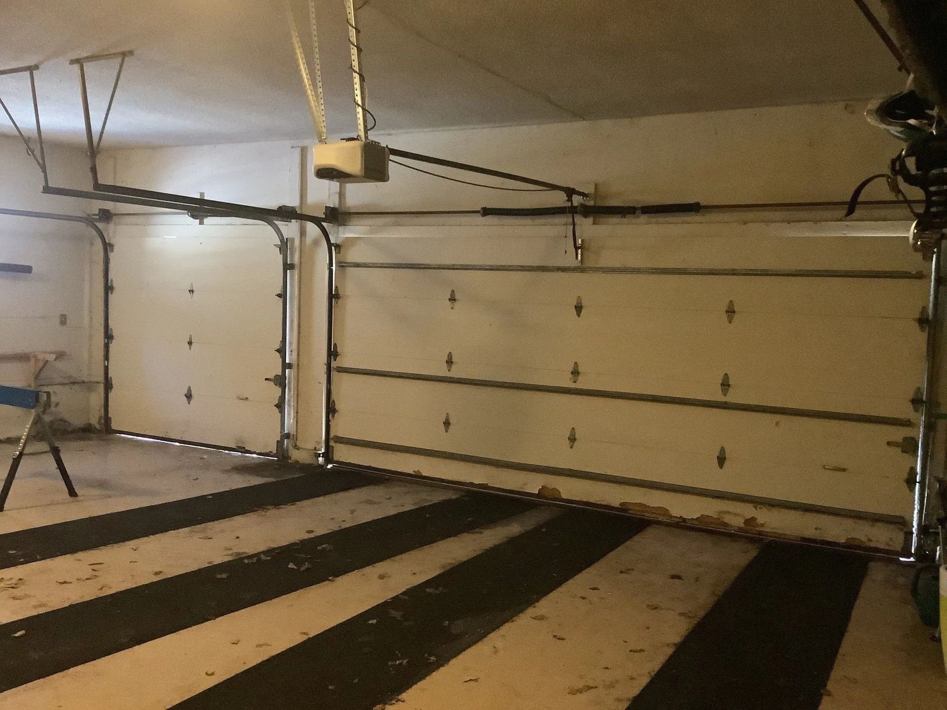 A garage with a striped floor and a garage door open