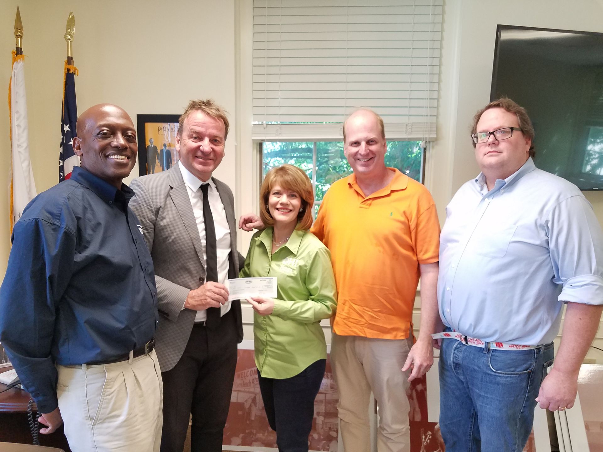 A group of people are posing for a picture with a woman holding a check.