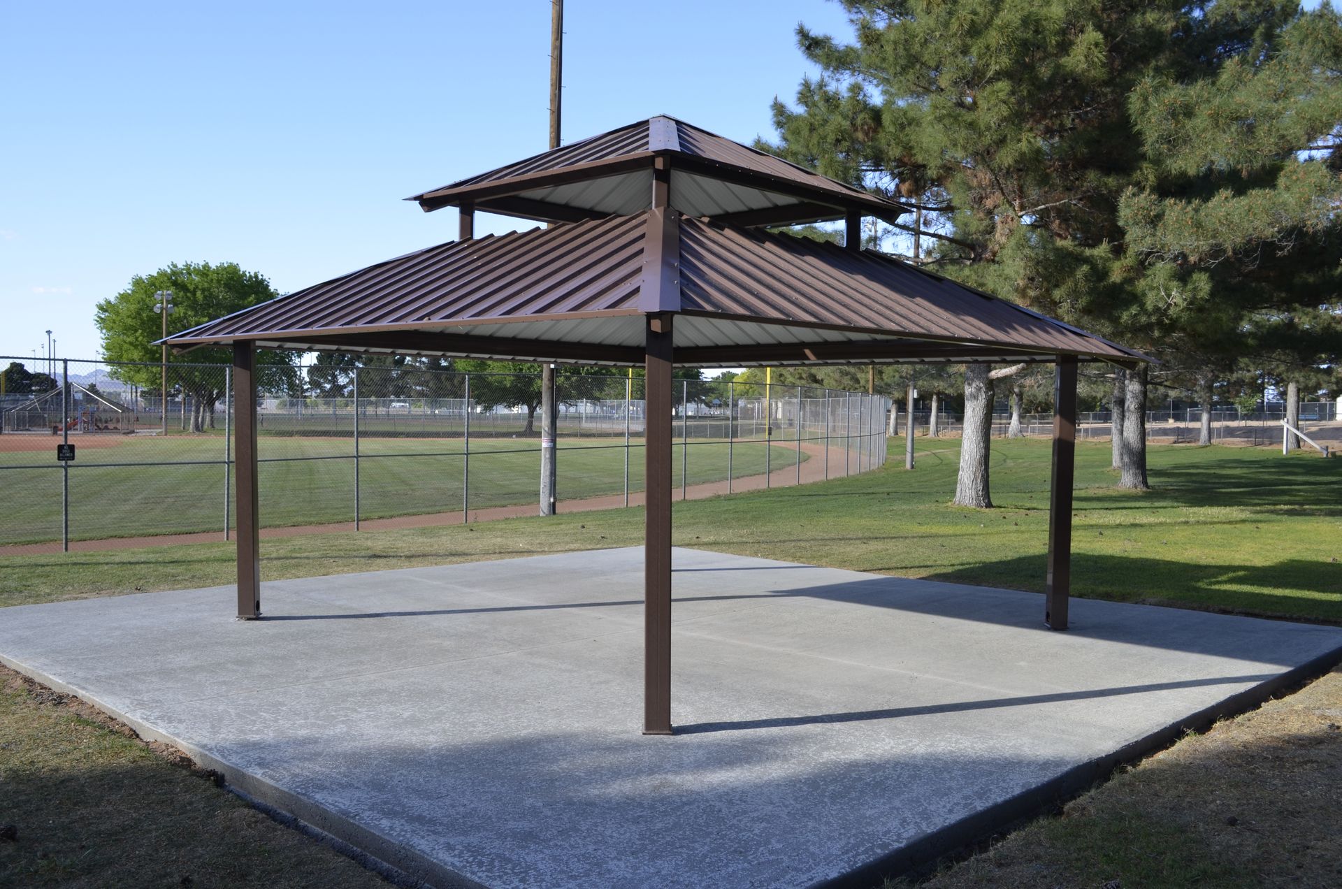 A gazebo in a park with trees in the background