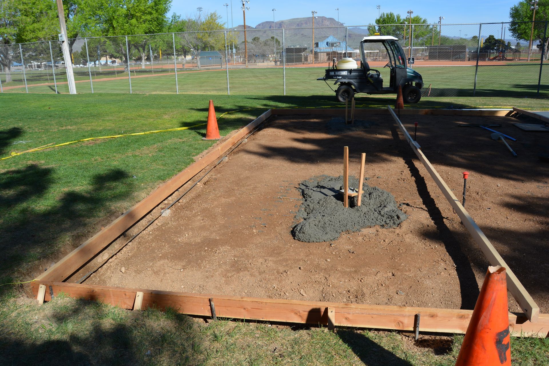 A construction site in a park with a golf cart in the background