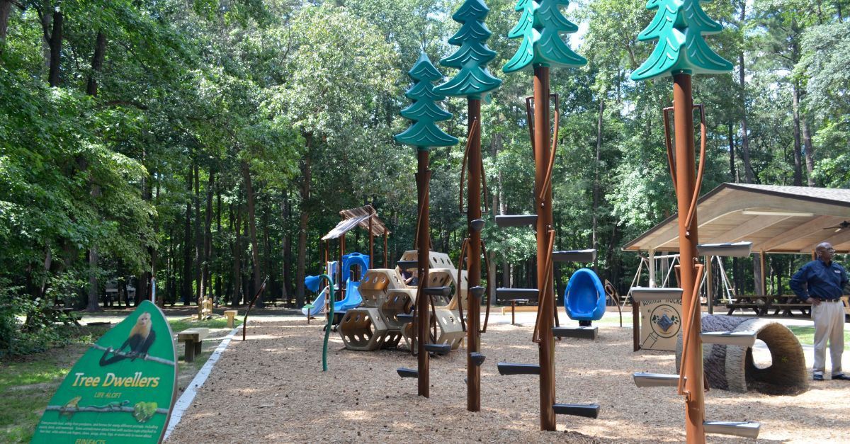 A playground in a park with trees and a sign that says fire hydrant