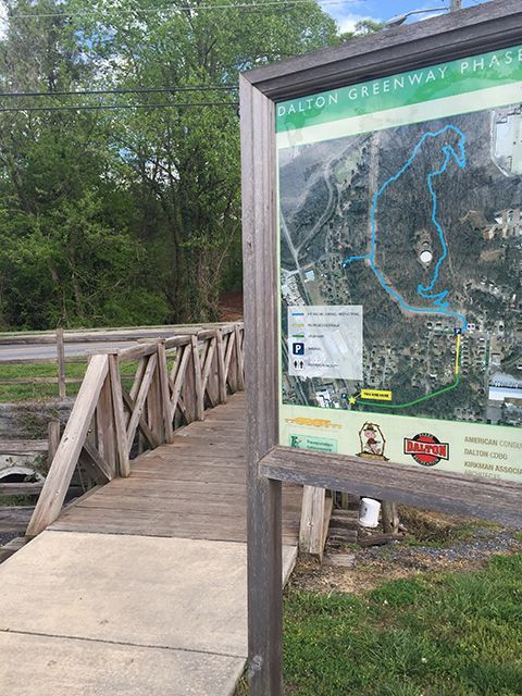 A map of a park is sitting next to a wooden bridge.