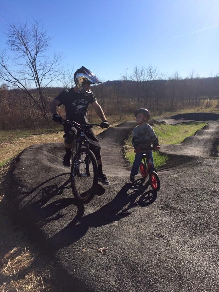A man is riding a bike next to a little boy who is riding a bike.
