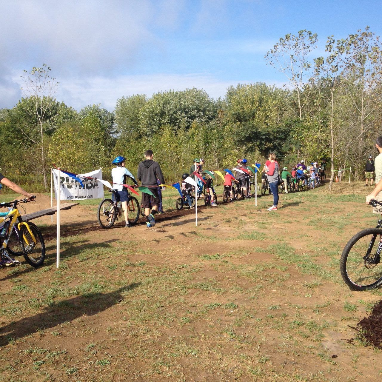 A group of people are riding bicycles in a field with a sign that says ' altitude ' on it