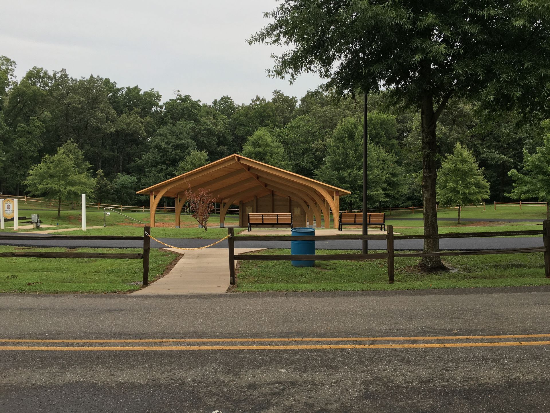 A pavilion in a park with a blue trash can in front of it