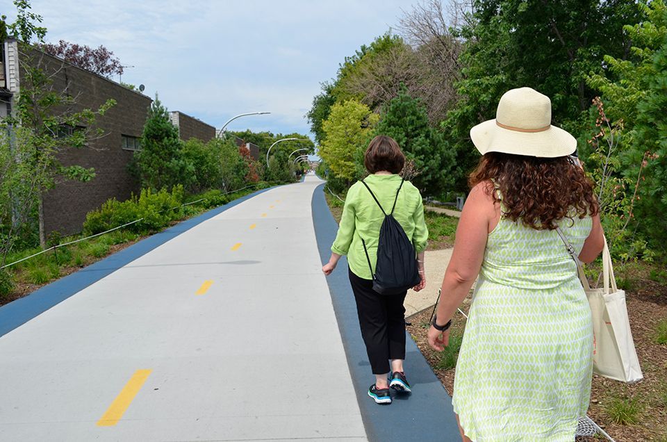Two women are walking down a sidewalk wearing hats.