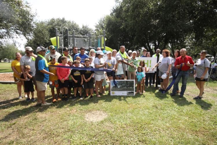 A group of people are standing in a park cutting a ribbon