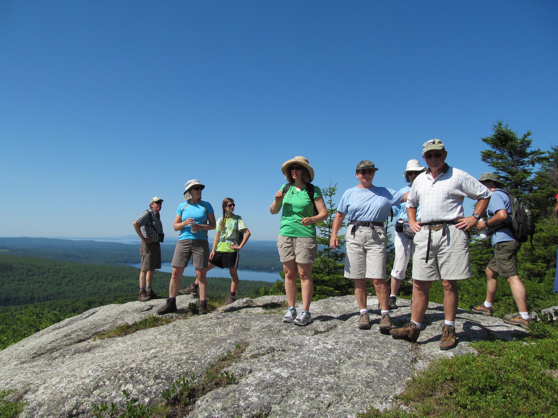 A group of people are standing on top of a rocky hill.