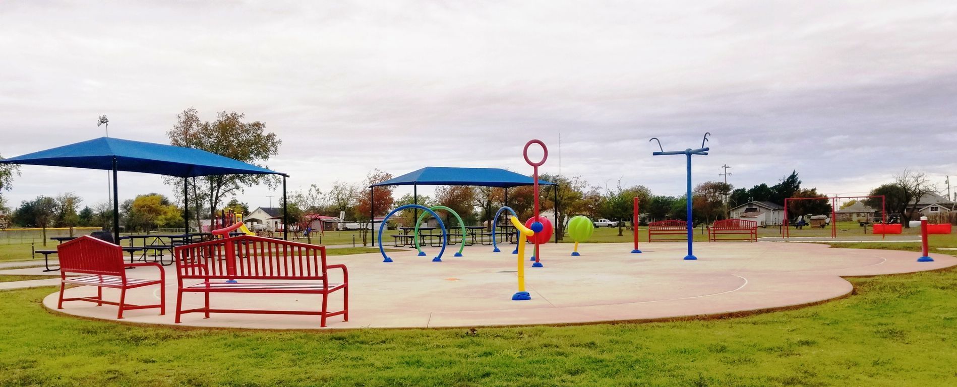 A playground in a park with benches and umbrellas