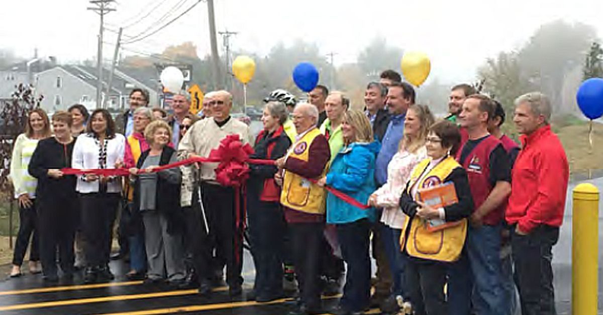 A group of people are standing in front of a ribbon cutting ceremony.