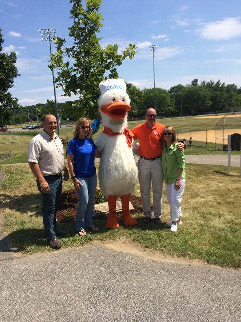 A group of people standing next to a duck mascot