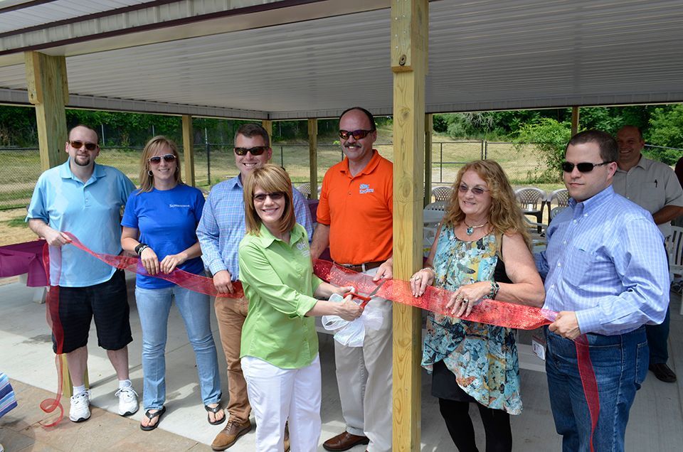 A group of people are cutting a red ribbon