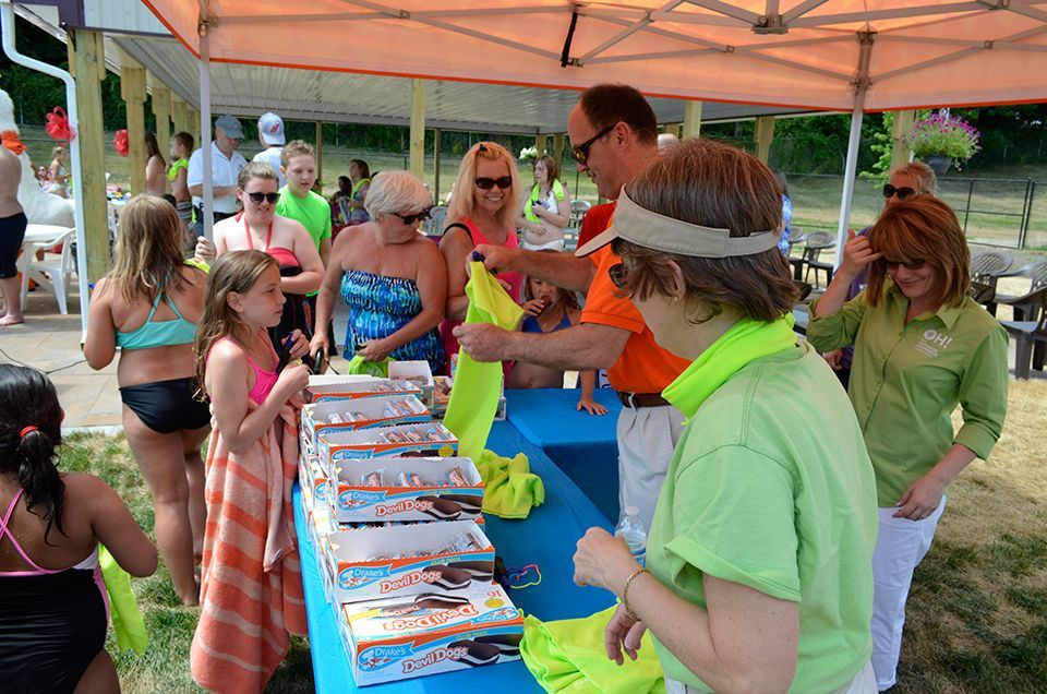 A group of people are standing around a table with boxes of pizza on it.