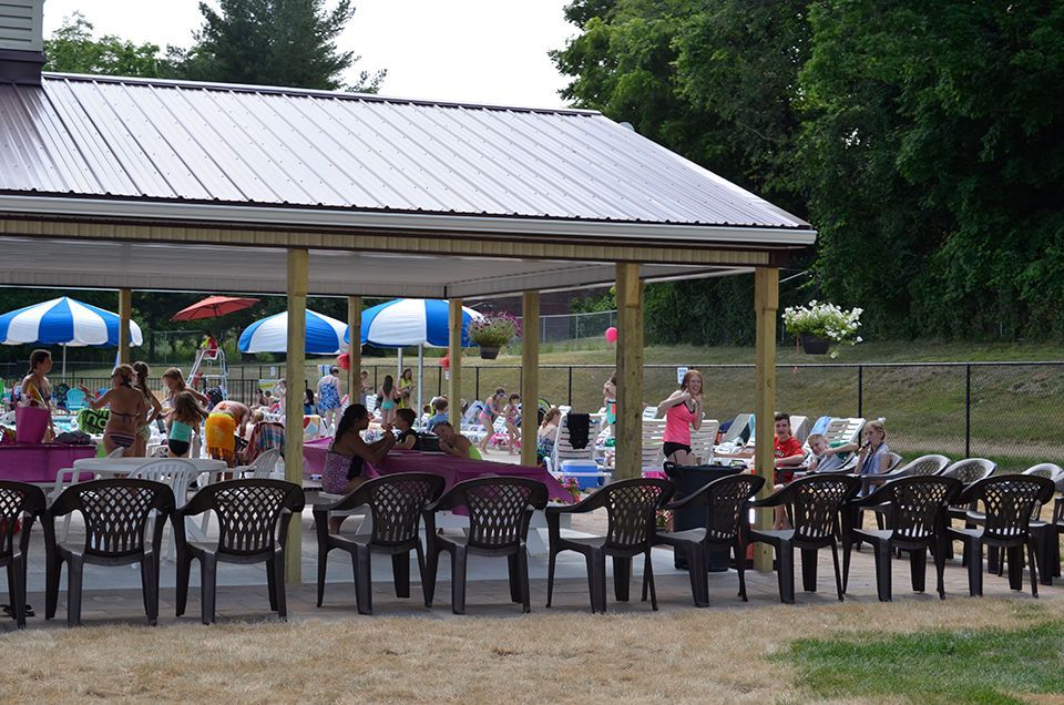A group of people are sitting under a pavilion with tables and chairs