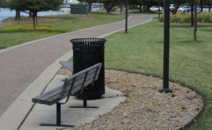 A park with a bench and a trash can