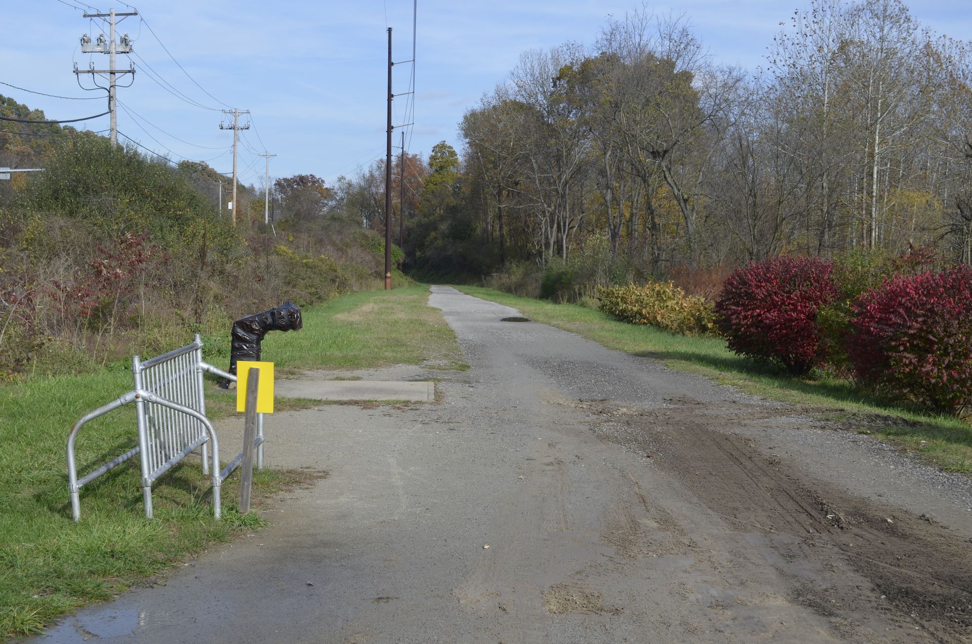 A bench is sitting on the side of a road next to a railroad crossing.