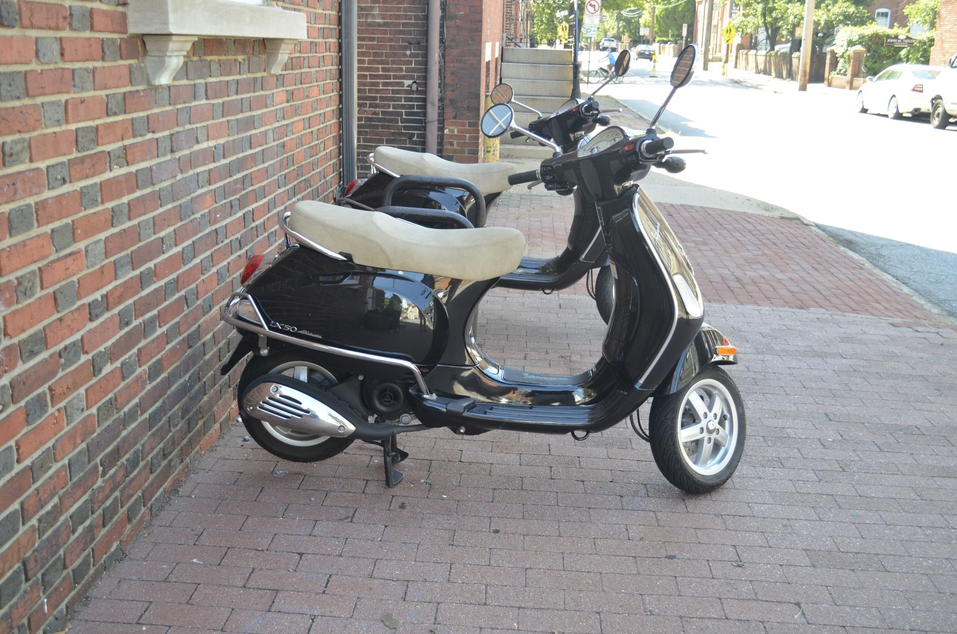 Two scooters are parked next to each other in front of a brick building