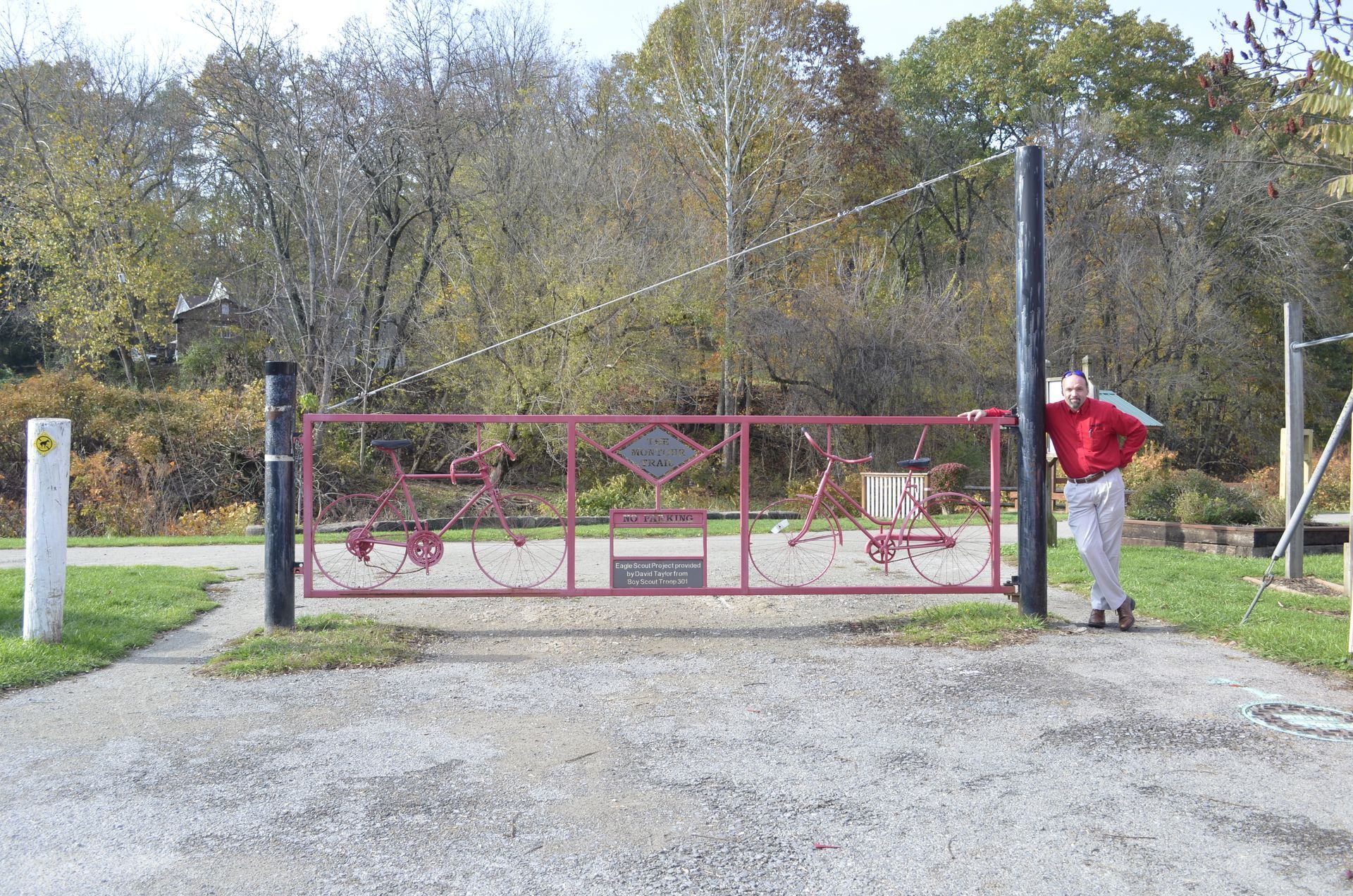 A man in a red shirt is standing in front of a red gate