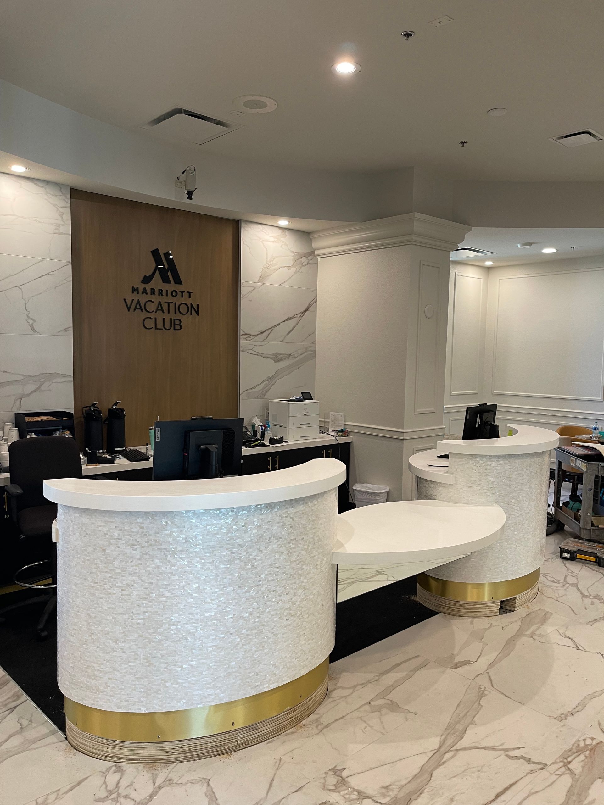 Modern reception area at Marriott featuring a luxurious white stone desk with gold accents and a marble backdrop.