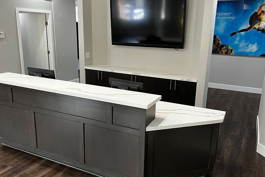 A reception desk with a flat screen tv on the wall above it.