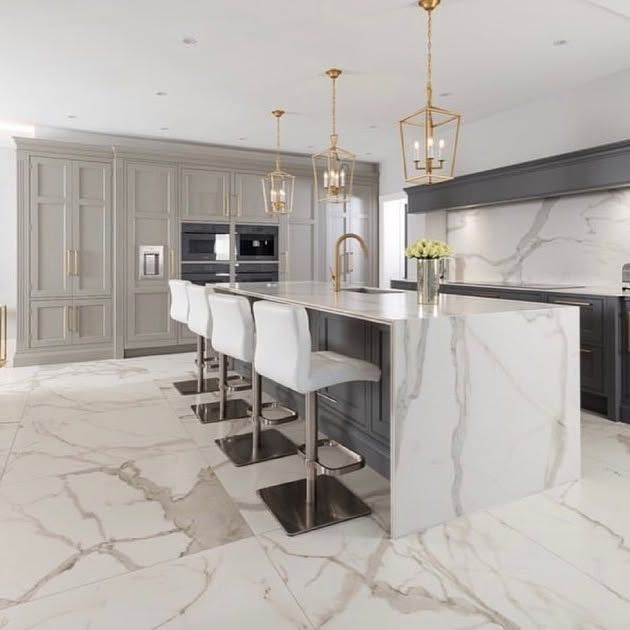 A kitchen with a large island and white chairs