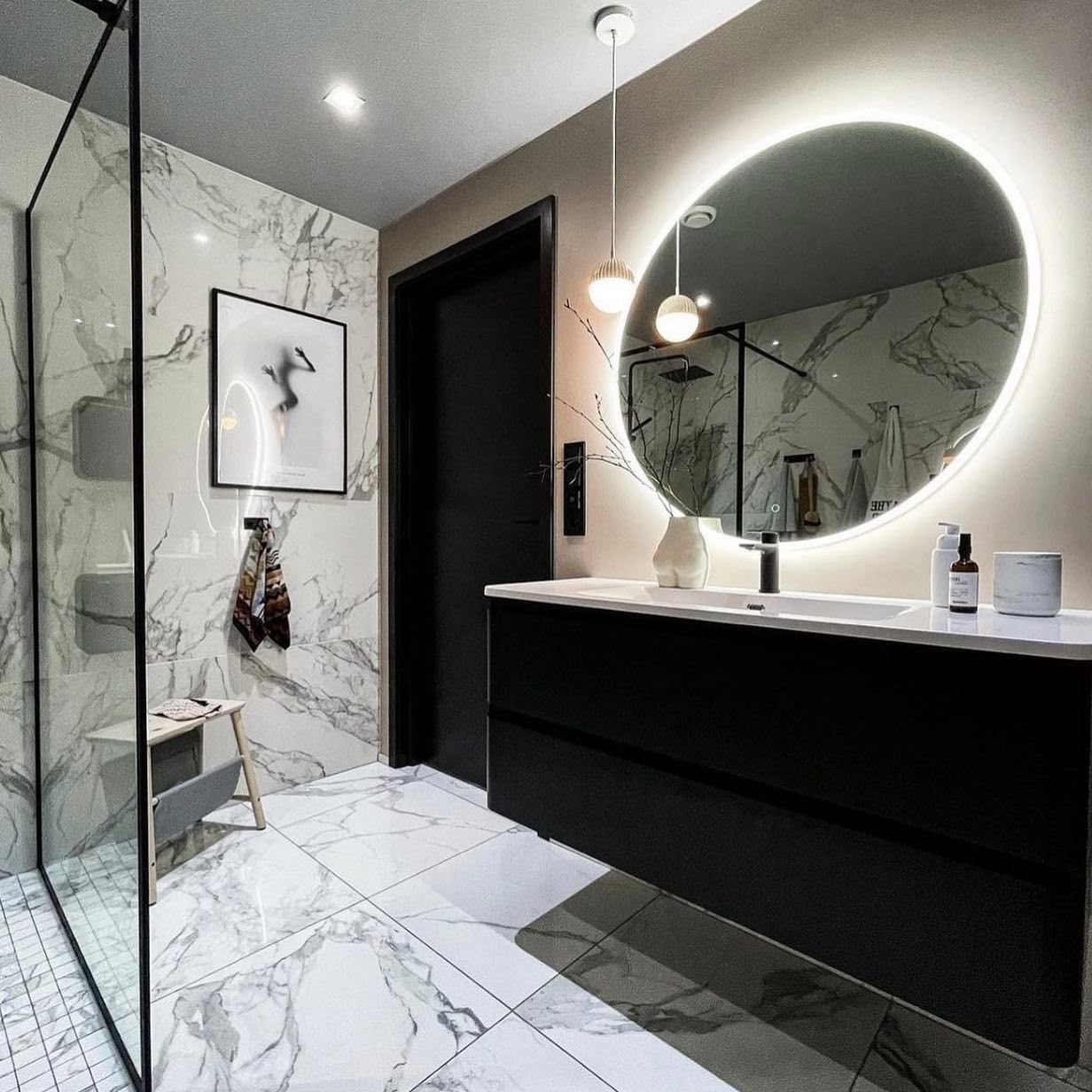 A bathroom with a sink and a round mirror