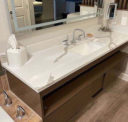 A bathroom vanity with a sink , mirror and soap dispenser.