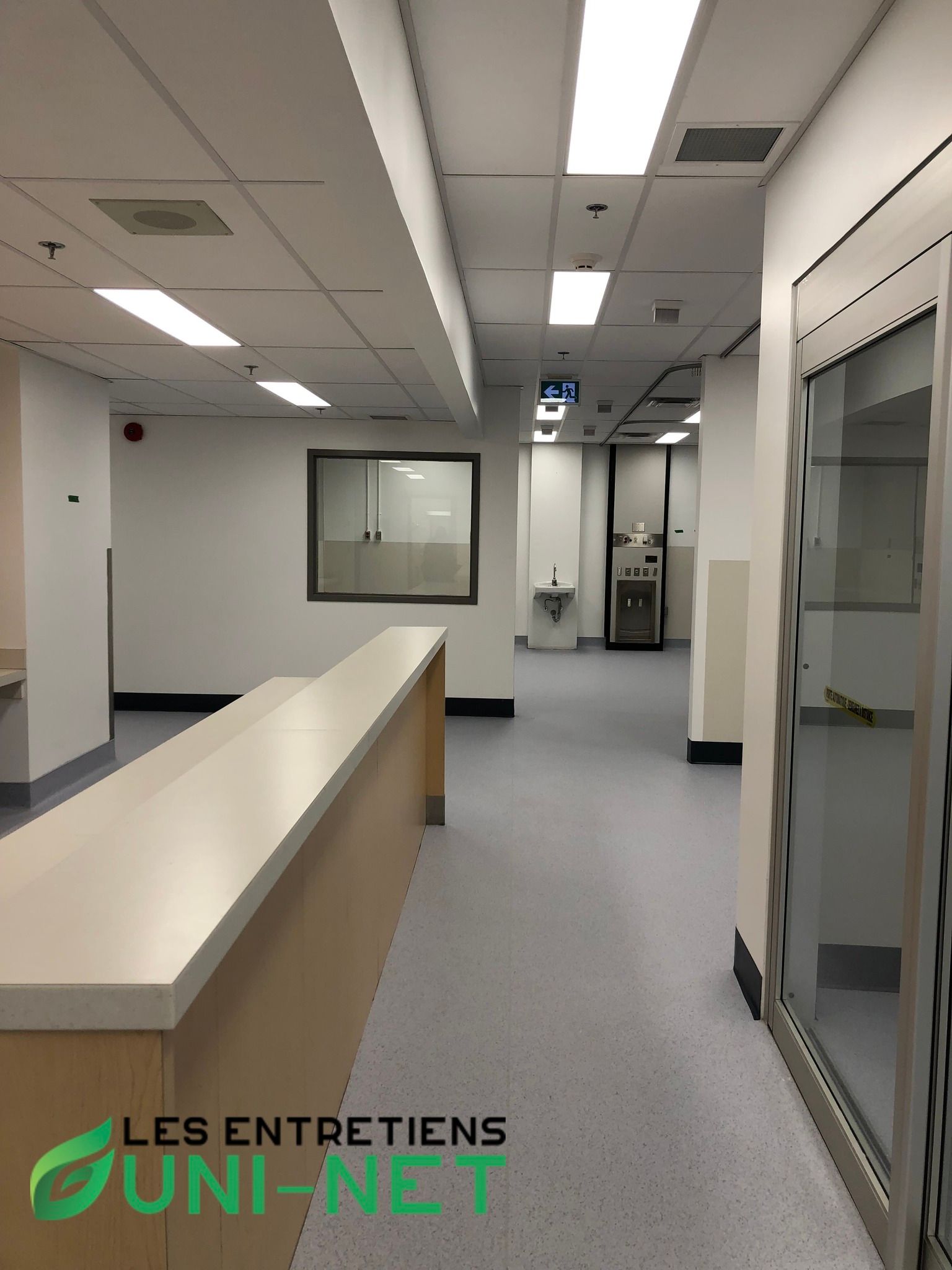 Long couloir aux murs blancs, éclairage au plafond et comptoir.