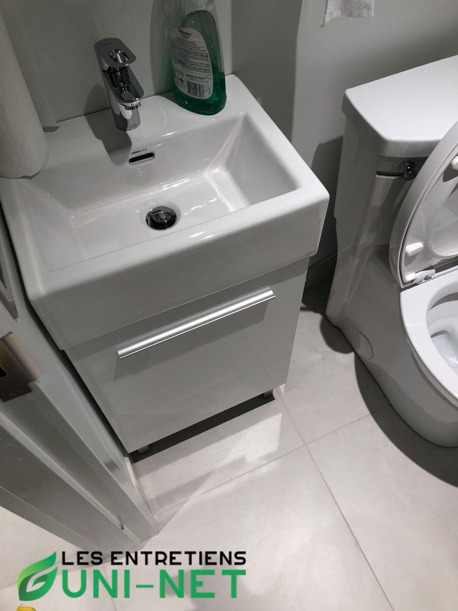 Petit lavabo blanc avec meuble de salle de bain à côté de toilettes blanches.