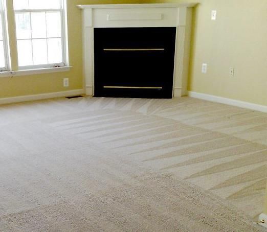 A vacuum cleaner is cleaning a carpet in a living room.